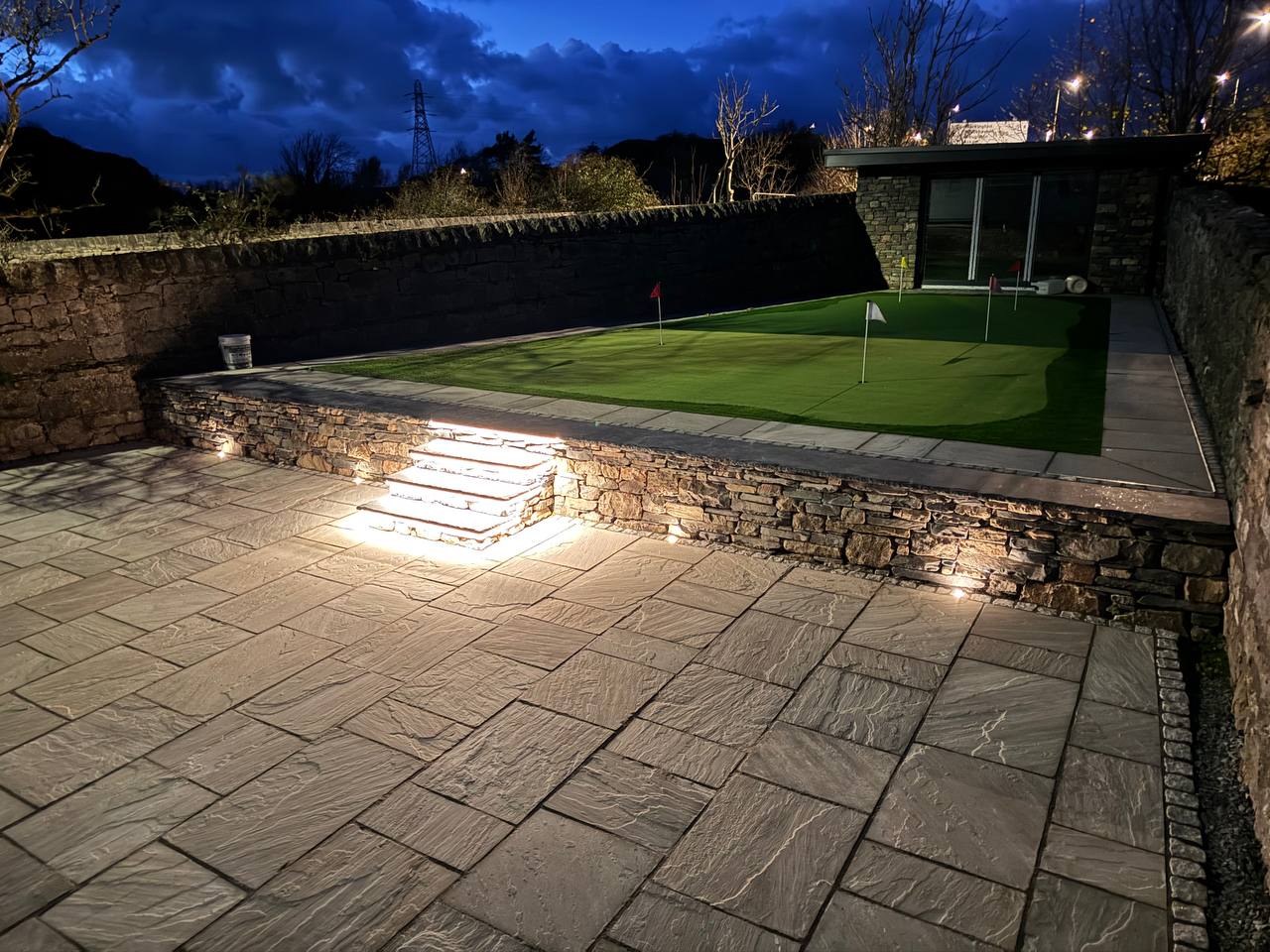 High-end landscaped garden with stone walling, patio lighting and putting green by Sam Shaw Kilburn Stonework Ltd